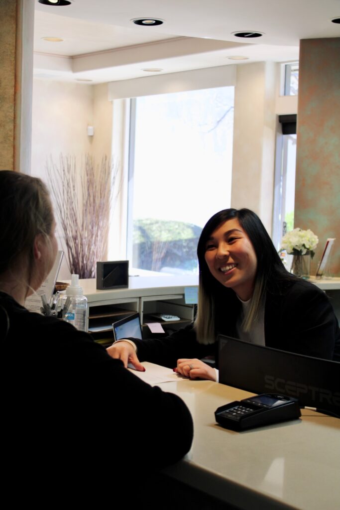 Front desk receptionist warmly speaking to a patient, symbolizing friendly and welcoming service on the First Visit page at Encinitas Dental Art.