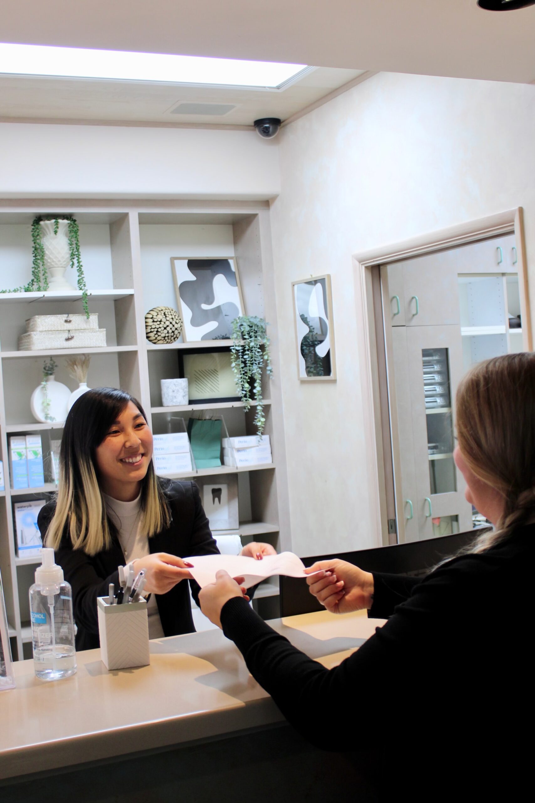 Receptionist handing paperwork to a patient, demonstrating efficient patient service on the First Visit page at Encinitas Dental Art.