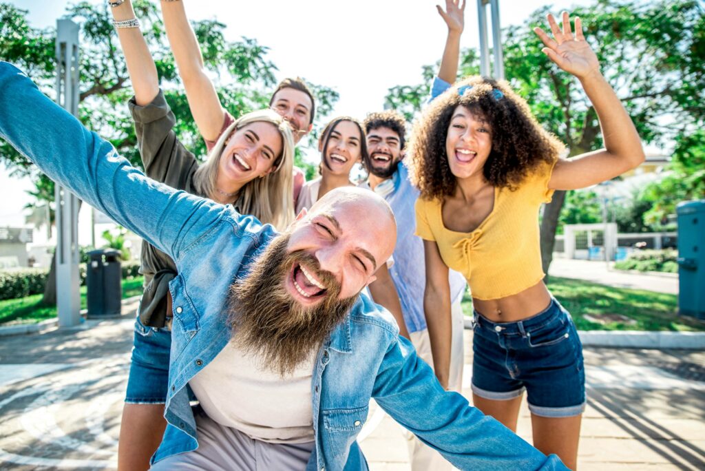 Group of friends smiling with raised arms, signifying the joy of improved dental aesthetics with inlays and onlays at Encinitas Dental Art.